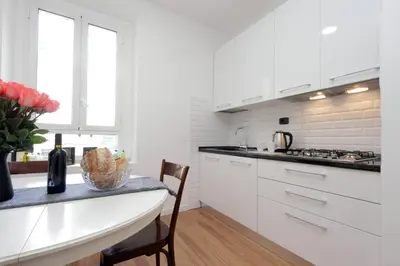 a kitchen with white cabinets and a table with a vase of flowers at Monti Central Apartment in Rome