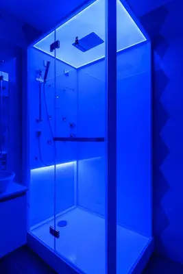 a bathroom with a glass shower with blue lighting at Sylvia Stylish Vatican Apartment in Rome
