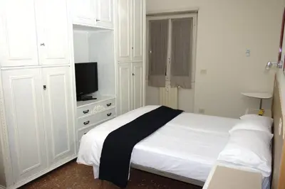 a white bedroom with a bed and a television at In vacanza da Sara in Rome
