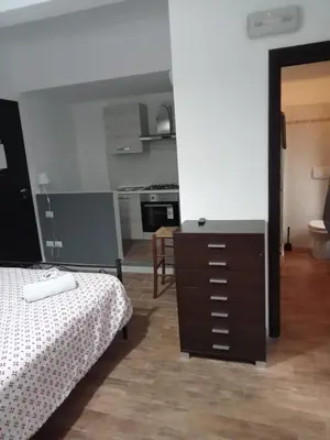 a bedroom with a bed and a dresser and a kitchen at Marco E Laura Affittacamere al Vaticano in Rome