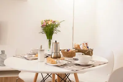 a white dining room table with food and flowers on it at Miani House in Rome