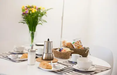 a table with cups and plates of food and a vase of flowers at Miani House in Rome