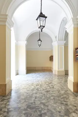 an empty room with a stone floor and a chandelier at Vatican House in Rome