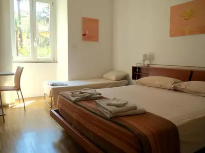 a bedroom with two beds and a chair and a window at WellnessINNrome shortlet in Rome