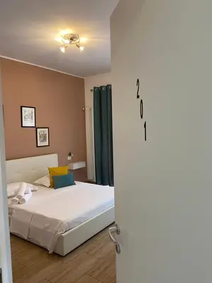 a bedroom with a bed with white sheets and green curtains at Juna's guest house in Rome