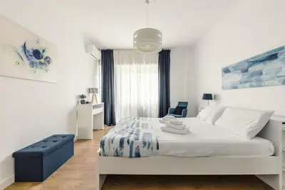 a white bedroom with a bed and a blue chair at Apartment Costanza in Rome in Rome
