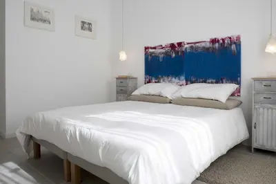 a bedroom with a white bed with a blue painting on the wall at Tempo Lento in Rome