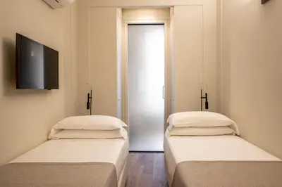 two beds in a room with a television on the wall at Hotel Smeraldo in Rome