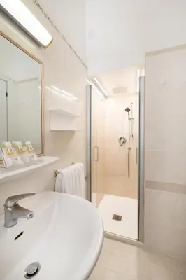 a white bathroom with a sink and a shower at Hotel Santa Prisca in Rome