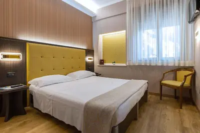 a bedroom with a large white bed and a chair at Hotel Santa Prisca in Rome