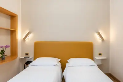 two beds in a room with two lights on the wall at Hotel Santa Prisca in Rome