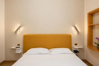 a bed with a yellow headboard and two white pillows at Hotel Santa Prisca in Rome