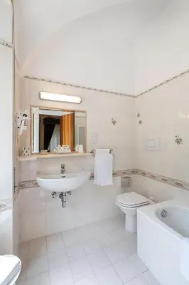 a white bathroom with a sink and a toilet at Hotel Santa Prisca in Rome