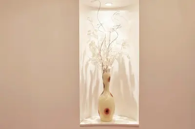 a white vase with flowers in it on a shelf at Vatican Luxury Penthouse with Terrace in Rome