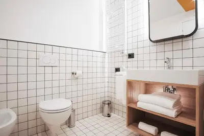 a white tiled bathroom with a toilet and a sink at Aparthotel Colombo Roma in Rome