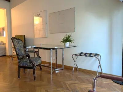 a table with a chair and a potted plant on a wall at Penna Apartment in Rome