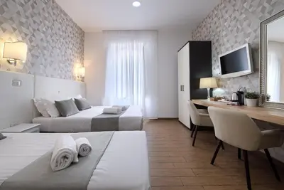 a hotel room with two beds and a desk at Domus Pietro Inn in Rome
