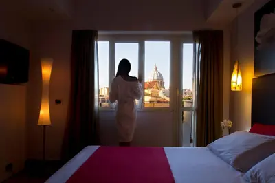 a woman standing in a hotel room looking out the window at Hotel Gravina San Pietro in Rome