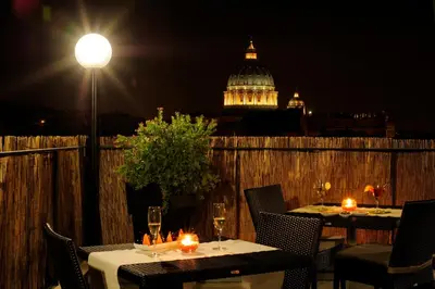 a couple of tables with candles on a balcony at night at Hotel Gravina San Pietro in Rome