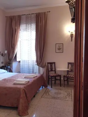 a bedroom with a bed and a table and a window at Maison de Marta in Rome