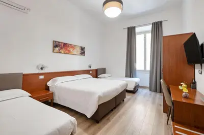 a hotel room with two beds and a desk at Principe Guesthouse in Rome