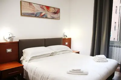 a bedroom with a bed with white sheets at Principe Guesthouse in Rome