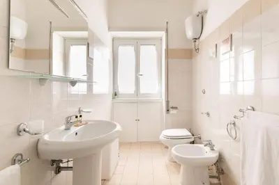 a white bathroom with a sink and a toilet at Goldie in Rome