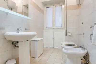 a white bathroom with a sink and a toilet at Goldie in Rome