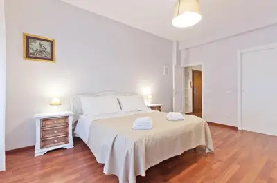 a white bedroom with a bed and a wooden floor at Liberty Trastevere B&B in Rome