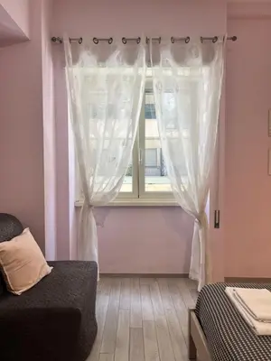 a bedroom with a window with white curtains at la casetta dei sogni in Rome