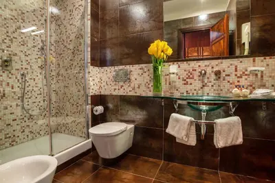 a bathroom with a sink toilet and a vase of yellow flowers at Hotel Memphis in Rome