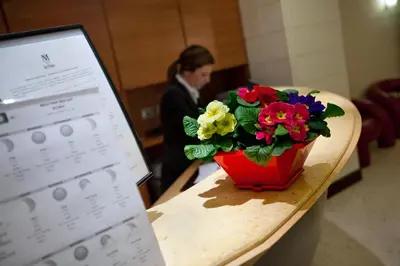 a woman standing behind a table with a vase of flowers at Hotel Memphis in Rome