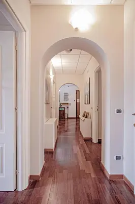 a hallway with an archway in a white room with wood floors at Domus Palatina in Rome