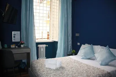 a bedroom with a bed with blue walls and a window at My Rhome Prati in Rome