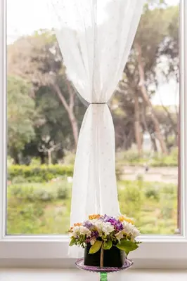 a vase with flowers in front of a window at Duke's Apartment in Rome