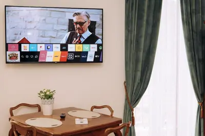 a television hanging on a wall above a table at Duke's Apartment in Rome