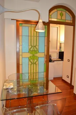 a glass table in a room with a stained glass window at La Petite Maison Piave in Rome