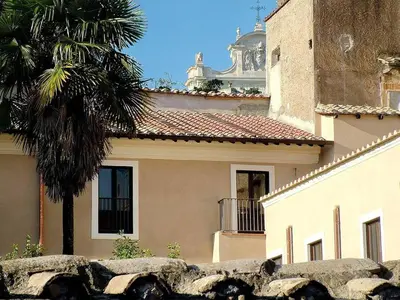 a building with a palm tree next to a wall at Trastevere Charming Loft | Romeloft in Rome