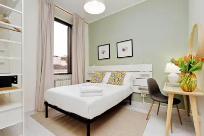 a white bedroom with a bed and a desk and a chair at Casa Santa Sofia in Rome