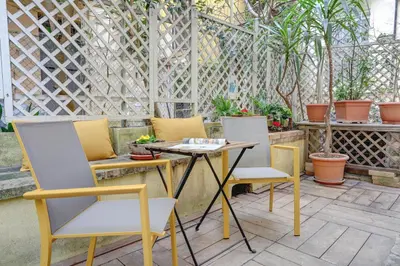 a patio with three chairs and a table and a fence at Colosseo Secret Garden - Home and More in Rome