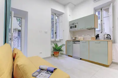 a living room with a couch and a kitchen at Colosseo Secret Garden - Home and More in Rome