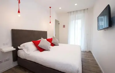 a bedroom with a white bed with red pillows at Vatican Modern Apartments KALASA in Rome