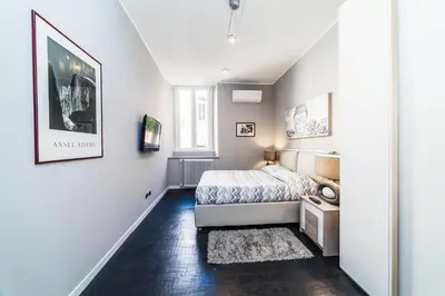 a white bedroom with a bed and a rug at Balestra Palace Apartment in Rome