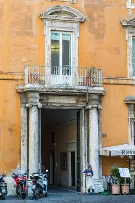 a man standing under a balcony on a building with two motorcycles at Balestra Palace Apartment in Rome