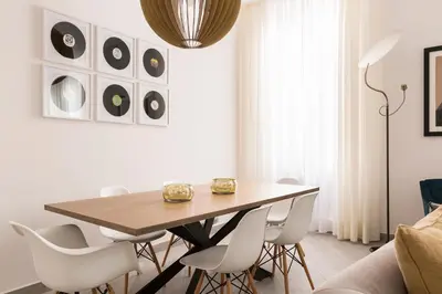 a dining room with a wooden table and white chairs at Maison Letizia Roma in Rome