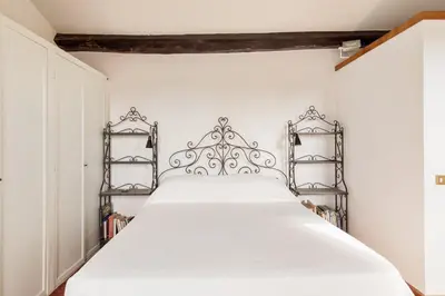 a bedroom with a white bed with two metal shelves at Piazza Mattei Terrace Apartment | Romeloft in Rome
