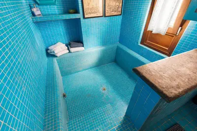 a blue tiled bathroom with a tub and a sink at Piazza Mattei Terrace Apartment | Romeloft in Rome