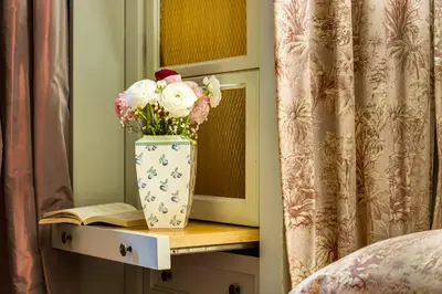a vase of flowers on a table with a book at Casa Heberart Guest House Sistina in Rome