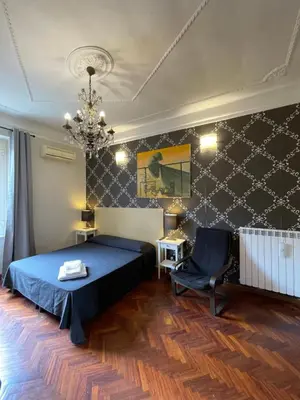a bedroom with a bed and a chair and a chandelier at Santa Bibiana B&B in Rome