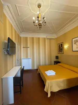 a hotel room with a yellow bed and a chandelier at Santa Bibiana B&B in Rome